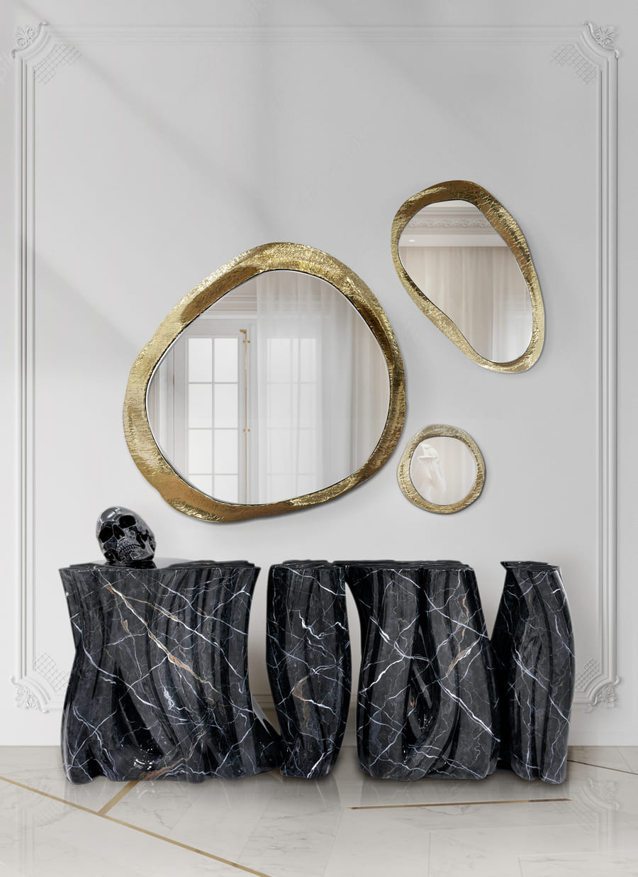 A luxurious entryway with a black marble console and gold mirrors.