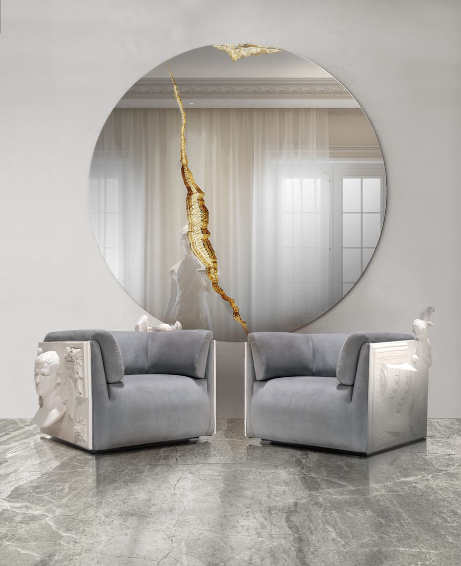 A luxurious living room with a gold mirror and white and grey armchairs.
